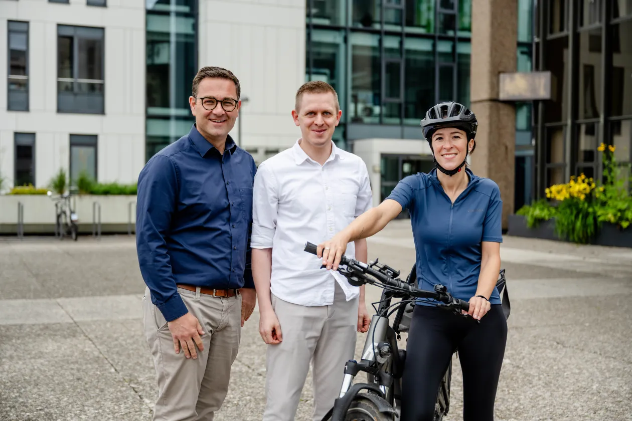 drei personen, eine frau mit helm und fahrrad