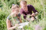 Studentin und Student im Gras schauen Blumen an