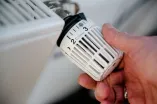 Hand am Regler einer Heizung