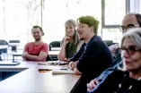Fünf Menschen sitzen am Tisch und diskutieren lächelnd