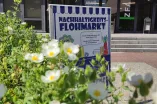Ein Plakat wirbt für den Nachhaltigkeitsflohmarkt, im Vordergrund Blumen