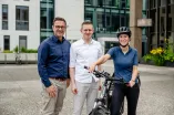 drei personen, eine frau mit helm und fahrrad
