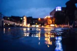 Pfütze auf Unibrücke wird bei Dunkelheit von Laternen angestrahlt