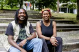 Die Gründer des Start-ups Bissap: ein junger Mann mit Rastalocken sitzt links auf Stufen; eine junge Frau mit buntem Kopftuch sitzt neben ihm; 