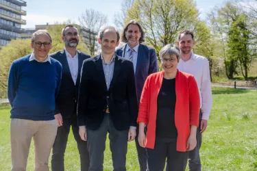 Gruppenbild: fünf Männer und eine Frau stehen auf einer Wiese